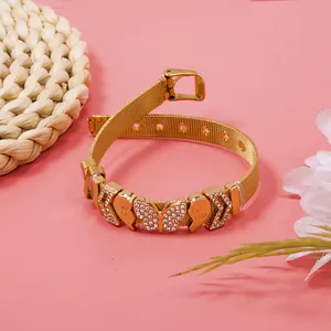 Close-up of gold mesh bracelet with sparkling rhinestone butterfly and heart charms.