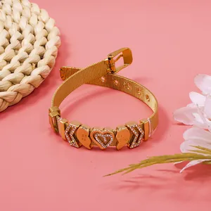 Detail view of a golden mesh bracelet with rhinestone heart and Best Friend charms.