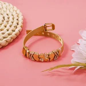 Detailed view of gold mesh bracelet with sparkling heart and clover charms