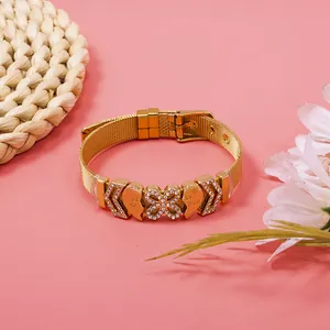 Macro view of gold mesh bracelet with rhinestone heart and butterfly charms detail.