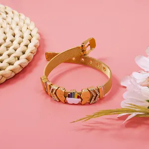 Macro detail of golden mesh bracelet with 'Best Friend' hearts and rainbow charm