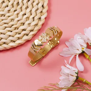 Detailed view of gold mesh bracelet featuring rhinestone clover and heart charms