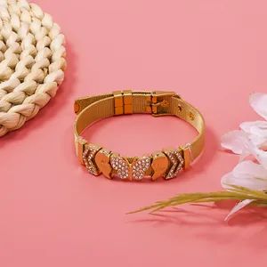 Detailed view of gold mesh bracelet featuring rhinestone butterfly and heart charms
