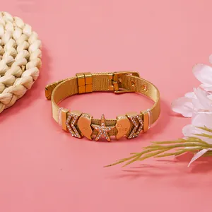 Detailed macro shot of a gold mesh bracelet with sparkling rhinestone heart and star charms.