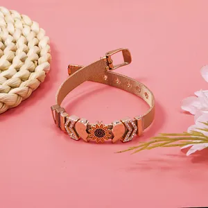 Detail shot of a rose gold mesh bracelet with sunflower and crystal heart charms.