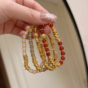 Gros plan de bracelets en agate naturelle avec des entretoises dorées et des détails dorés.