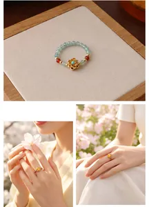 Detailaufnahme eines perlenbesetzten Natursteinrings mit elegantem goldenem Lotusmotiv.