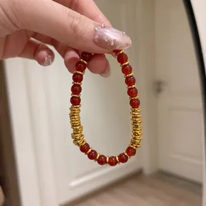 Gros plan détaillé d'un bracelet en agate rouge naturelle avec entretoises dorées.