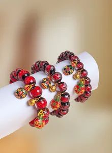 Gros plan de bracelets en perles de verre rouges avec breloques en émail et accents dorés
