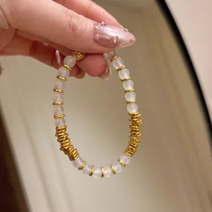 Vue macro détaillée montrant des perles d'agate blanche naturelle et des entretoises dorées