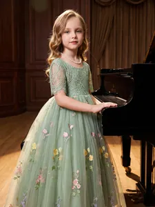 Detail of elegant green lace girl dress with flower and butterfly embroidery