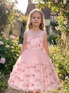 Elegant pink flower girl dress with floral embroidery shown in an outdoor garden setting.