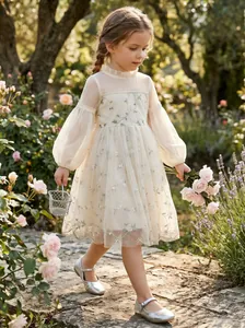 Elegant cream tulle flower girl dress with floral vine embroidery in a sunny garden.