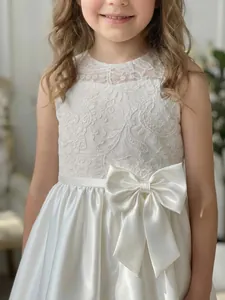 Nahaufnahme eines eleganten weißen Satin-Blumenmädchenkleides mit Spitzenoberteil.