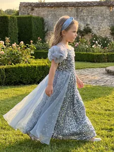 Full-length side view of a shimmering silver sequined girl's party dress in a garden