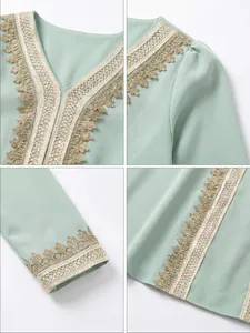 Detailed view of mint green girls' dress with ornate gold lace trim