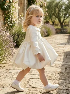 Elegant cream satin flower girl dress featuring long sleeves and a classic Peter Pan collar.