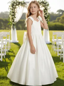 Elegante abito bianco da damigella con grande fiocco in un giardino per matrimoni all'aperto.