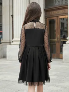 Vista posteriore di un elegante abito nero per bambina con maniche in mesh a pois e gonna.