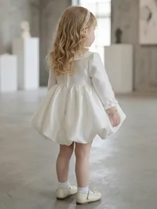 Rear view of an elegant white knee-length flower girl dress with bubble skirt and satin finish