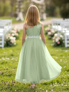Back view of a sage green flower girl dress with white lace waist in a garden setting