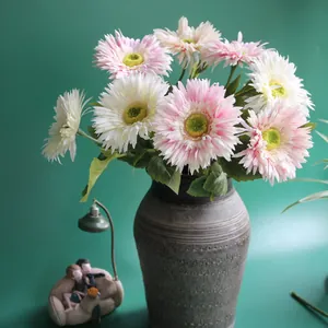 Detail view of pink and white artificial Gerbera daisies in a textured grey vase