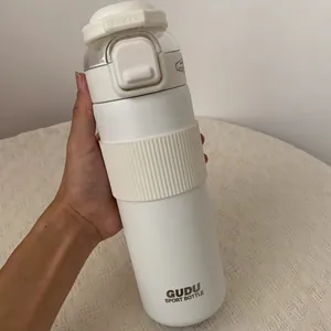 Hand-held close-up view of a white matte stainless steel sport bottle with GUDU logo
