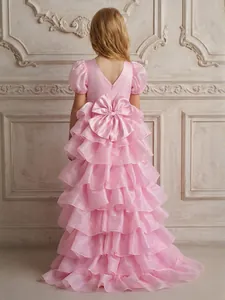 Back view of pink tiered ruffle flower girl gown with large bow and train detail