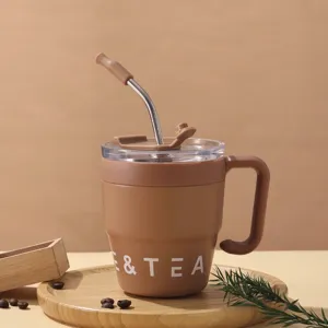 Detailansicht eines braunen Edelstahl-Kaffeebechers mit Metallstrohhalm und Griff.