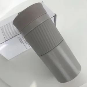 Gedetailleerd close-up van een grijze roestvrijstalen reiskoffiemok met antislip siliconen greep