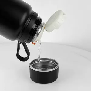 Borraccia sottovuoto in acciaio nero 316 che versa acqua nel coperchio della tazza