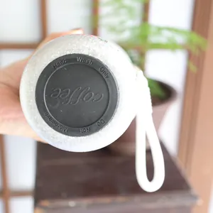 Detail view of the non-slip bottom of a white textured insulated coffee cup