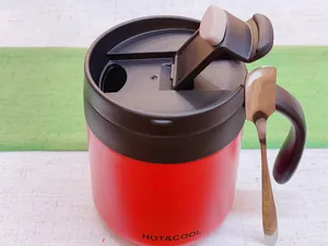 Close-up view of a red stainless steel insulated coffee mug with black lid and spoon