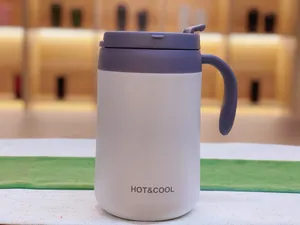 Macro view of a white stainless steel thermal mug with handle and purple lid detail.