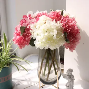Artificial hydrangea bouquet in vintage coral and white with a glass vase stand.