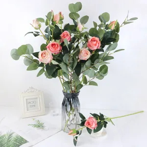 Ramo de rosas rosas artificiales con hojas de eucalipto en un jarrón de vidrio gris