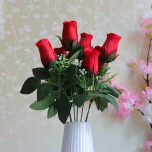Nahaufnahme von künstlichen roten Seidenrosen mit sieben Blütenköpfen in weißer Vase