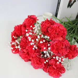 Detalle de primer plano de claveles rojos artificiales realistas con flores de gipsofila