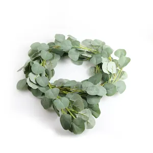 Gros plan d'une guirlande de feuilles d'eucalyptus artificielles sur un fond blanc.
