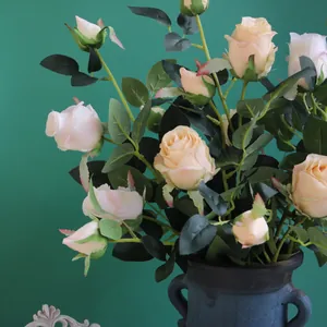 Détail de roses artificielles bulgares vintage dans un vase bleu rustique sur fond vert