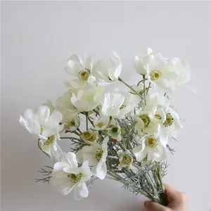Primo piano di fiori di cosmo artificiali bianchi con petali di seta e steli verdi.