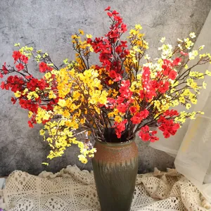 Vista detallada de flores de gipsófila artificiales rojas y amarillas en jarrón de cerámica