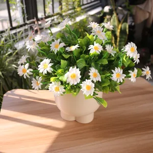 Detailed view of artificial white daisies in a pot on a sunlit wooden table