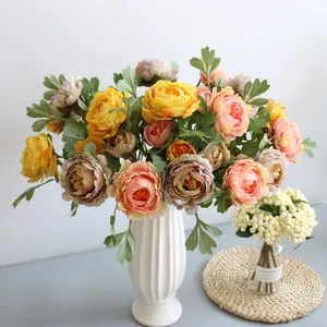 Close-up of silk artificial Ranunculus bouquet in a white ribbed vase for home decor.
