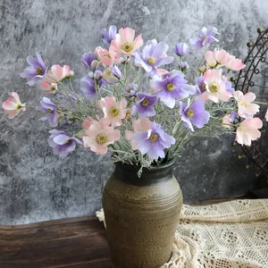 Vista dettagliata della composizione di cosmi in seta rosa e viola in un vaso rustico.