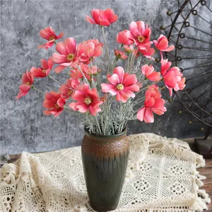 Dettaglio di fiori di cosmo rosa artificiali realistici in un vaso di ceramica decorato