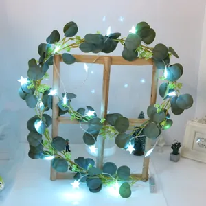 Detailed close-up of artificial eucalyptus leaf vine with glowing star LED fairy lights