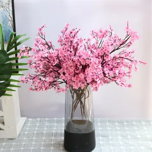 Rama de paniculata artificial de tela rosa en un jarrón de vidrio para decoración de boda