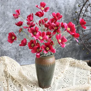 Primo piano di vivaci fiori di cosmo artificiali magenta in un vaso di ceramica rustica