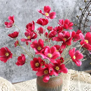 Primo piano di fiori di cosmo artificiali rossi in un vaso di ceramica rustico
